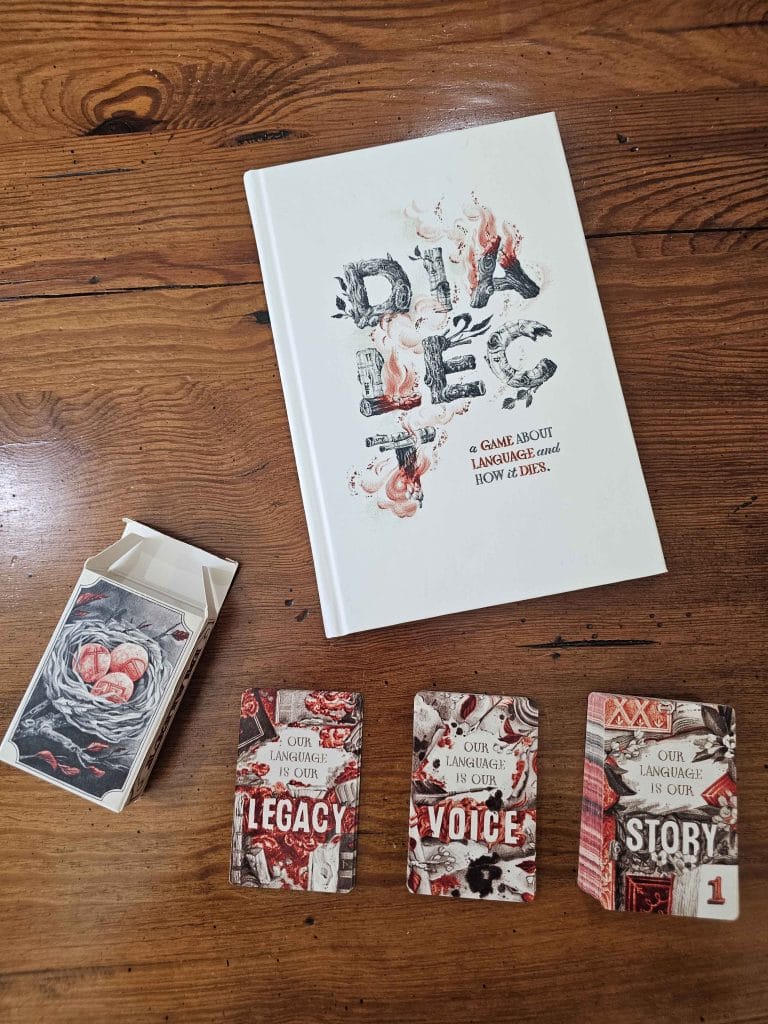 The Dialect TTRPG rulebook and cards, featured in an Assemblage TTRPG review.