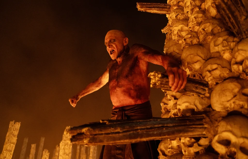 28 Years Later: The Bone Temple - Ralph Fiennes chanting next to a structure made up of human skulls