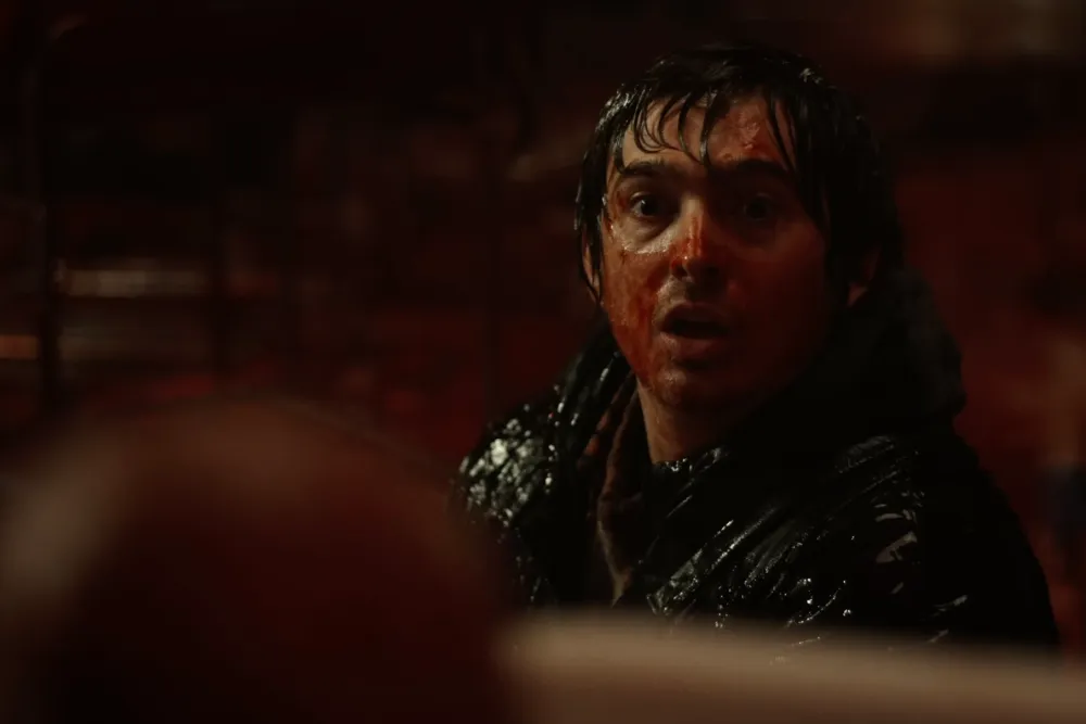 Resident Evil (2026 film) - Bryan, covered in blood, looks in mild horror at something off screen